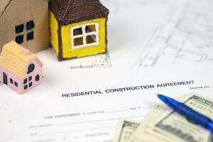 Residential construction agreement ready to sign with small toy houses and pen. Construction contract photo