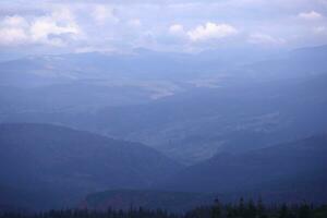 Morning view from the Dragobrat mountain peaks in Carpathian mountains, Ukraine. Cloudy and foggy landscape around Drahobrat Peaks photo