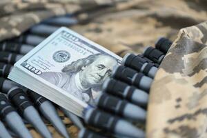 Bundles of dollars and a machine gun belt on the camouflage uniform of a Ukrainian soldier. Concept of war financing, bribe or donation photo