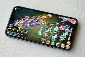 Fantasy Westward Journey mobile iOS game on iPhone 15 smartphone screen on wooden table during mobile gameplay photo