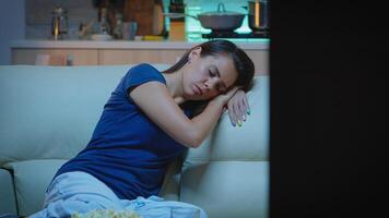 Portrait of woman sleeping on couch in living in front of television. Tired exhausted lonely sleepy lady in pajamas falling asleep sitting on cozy sofa, closing eyes while watching movie at night. photo