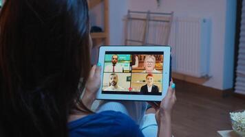 Back view of woman on videocall sitting on comfortable couch. Remote worker having online meeting consulting with colleagues on video conference and webcam chat using internet technology. photo