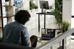 Startup employee having virtual conference with ceo on laptop in coworking space. Arab company employee chatting with team leader on portable computer screen in business office photo