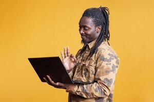 African american man reading good news on laptop computer, browosing webpages on internet. Young adult working atr online project, searching business information on digital device photo