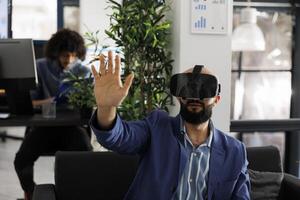 Executive manager using vr glasses for strategy testing in metaverse while working in coworking space. Entrepreneur exploring virtual reality and brainstorming in business office photo