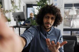Confused start up company product manager discussing project with client on smartphone videocall and looking at camera. Business entrepreneur explaining analytics report to customer on mobile phone photo