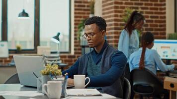 African american man planning reports, working with executive data analytics in coworking space. Business manager reading official company statistics before making important decisions. photo