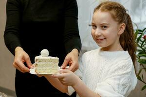 alegre niña participación un plato con un pedazo de hecho en casa pastel en su manos foto