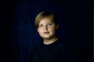 A concise portrait of a European boy. Portrait on a dark background. photo