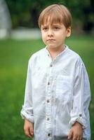 A young handsome boy of European appearance enjoys spending time on the green lawn at home. It's a great time to relax. photo