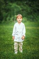 A young handsome boy of European appearance enjoys spending time on the green lawn at home. It's a great time to relax. photo