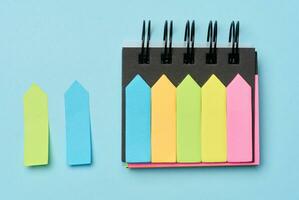 Multi-colored paper sticky notes on a blue background photo