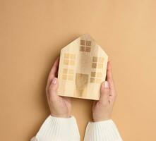 Wooden miniature model house on a brown background. Real estate insurance concept, environmental protection photo