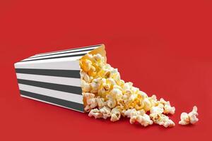 Tasty cheese popcorn falling out of a black striped carton bucket, isolated on red background photo