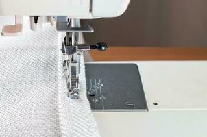 sewing machine. the process of sewing a decorative cord of white fabric. photo