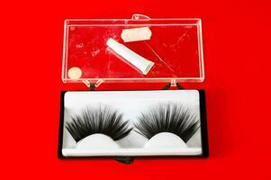 a pair of false eyelashes in a box on red photo