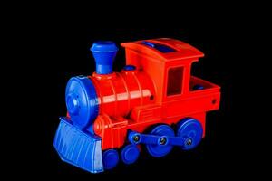 a toy train is red and blue on a black background photo