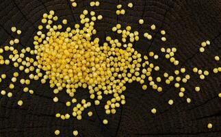 Heap of millet groats on black wooden background. Top view photo