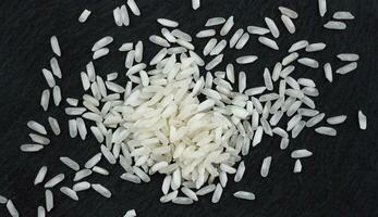 Heap of rice grains on black background. Top view photo