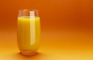 Glass of orange juice isolated on orange background with copy space photo