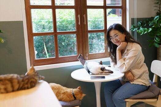 mujer trabajando desde hogar con gato. gato dormido en el ordenador portátil teclado. asistente gato trabajando a ordenador portátil foto