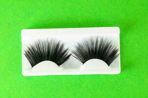 a pair of false eyelashes on a green background photo