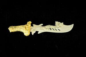 a carved gold and white knife with a dragon on it photo