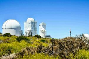 the telescopes are on top of a hill with bushes and trees photo