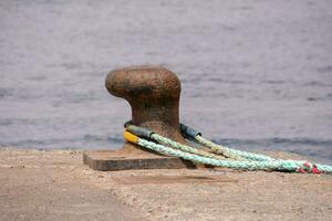 a rope tied to a metal post near the water photo