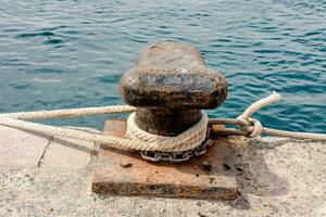 a rusted anchor on a dock with rope photo