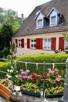 un casa con rojo persianas y flores en frente de eso foto