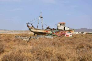 an old boat is sitting in the middle of a dry field photo