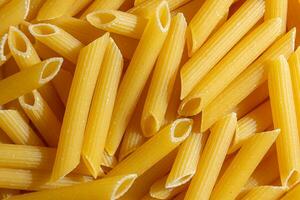Uncooked Penne Rigate Pasta. A Culinary Canvas of Penne Macaroni, Creating a Lively and Textured Background for Gourmet Cooking. Dry Pasta. Raw Macaroni - Top View, Flat Lay photo