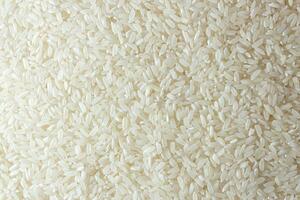 Dry Uncooked White Rice Background - Top View, Flat Lay. Scattered Raw Long Grain Rice. Asian Cuisine and Culture. Healthy Eating Ingredients. Diet Food photo