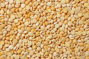 Uncooked Polished Split Peas Background. A Culinary Canvas of Dry Yellow Peas, Creating a Lively and Textured Background for Gourmet Cooking. Scattered Raw Polished Peas. Healthy Eating Ingredients photo