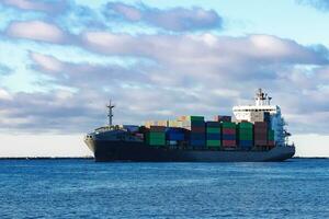 Modern grey container ship moving in still water photo