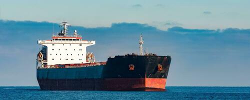 Black cargo ship moving in still Baltic sea water. Riga, Europe photo
