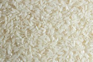 Dry Uncooked White Rice Background - Top View, Flat Lay. Scattered Raw Long Grain Rice. Asian Cuisine and Culture. Healthy Eating Ingredients. Diet Food photo