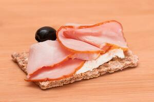 Whole Grain Crispbread with Ham, Cream Cheese and Olives on Bamboo Cutting Board. Easy Breakfast. Diet Food. Quick and Healthy Sandwiches. Crispbread with Tasty Filling. Healthy Dietary Snack photo