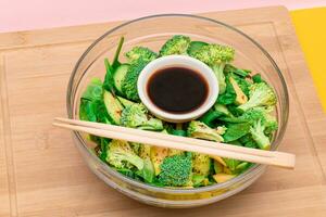 Fresh Green Salad of Avocado, Broccoli, Spinach and Cucumber for Detox with Soy Sauce on Wooden Cutting Board. Vegan Salad. Vegetarian Culture. Raw Food. Healthy Eating and Vegetable Diet photo