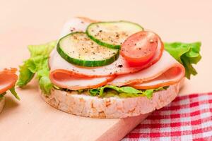 ligero desayuno. rápido y sano sándwiches arroz pastel con jamón, tomate, Fresco Pepino y verde ensalada en de madera corte tablero foto