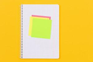 A Notepad with Sticky Notes Lying on Yellow Table Blank Template. Top View, Flat Lay photo