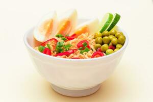 Beautiful Noodle Dish with Green Pea, Eggs, Red Hot Pepper, Greens and Lime on White Background. Instant Noodles photo