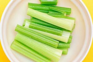 Fresh Chopped Celery Sticks with Water Drops in White Bowl Top View. Vegan and Vegetarian Culture. Raw Food. Healthy Diet with Negative Calorie Content photo