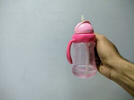 a pink children's drink bottle held in the right hand photo