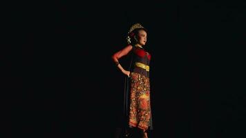 un asiatique femme des stands en toute confiance tandis que portant une batik costume et noir écharpe video