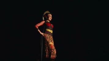 ein asiatisch Frau steht selbstbewusst während tragen ein Batik Kostüm und schwarz Schal video