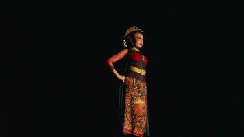 an Asian woman stands confidently while wearing a batik costume and black scarf video