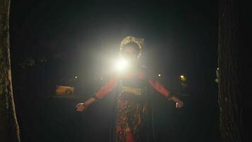 an Asian woman walks while dancing in front of the lights while wearing a bun in her black hair with gold accessories video