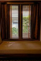 ligero viniendo mediante de madera ventana persianas dentro vivo habitación. foto